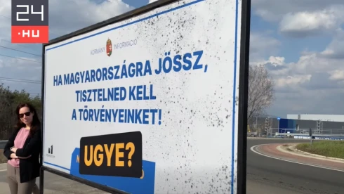 Korábbi nemzeti konzultációs üzenetet tartalmazó plakáttal tiltakozik a Momentum a gödi Samsungnál